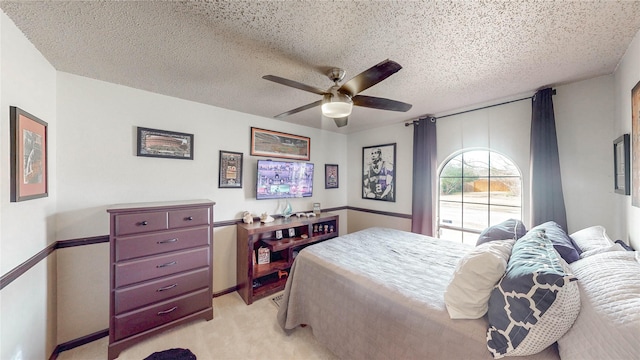 bedroom featuring ceiling fan, a textured ceiling, and light colored carpet