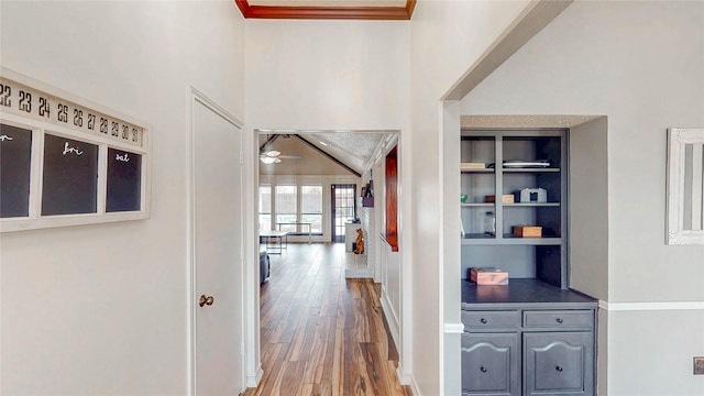 hall with baseboards, built in features, and wood finished floors