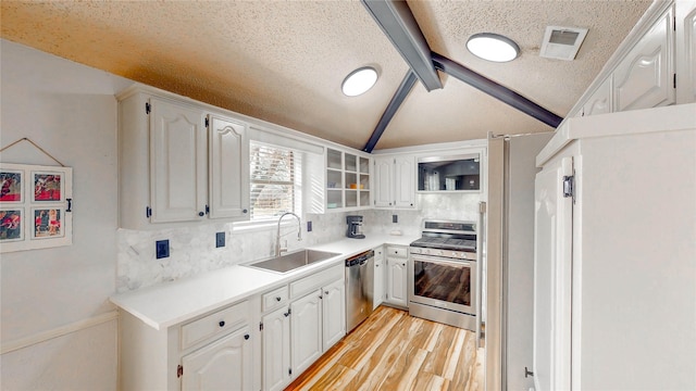 kitchen with light wood-style flooring, stainless steel appliances, a sink, visible vents, and vaulted ceiling