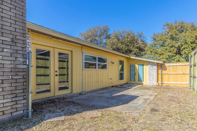 back of house with french doors, brick siding, fence, and a patio