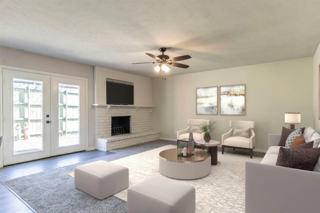 living room featuring a brick fireplace, baseboards, a ceiling fan, and french doors