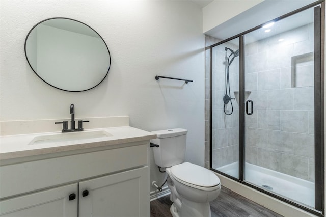 bathroom featuring a stall shower, vanity, toilet, and wood finished floors