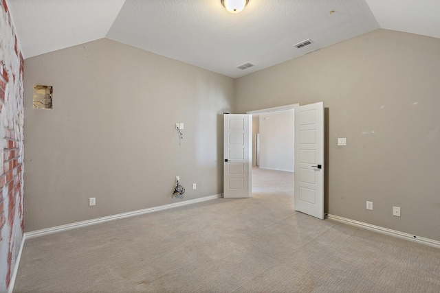 unfurnished room with visible vents, vaulted ceiling, light carpet, and baseboards