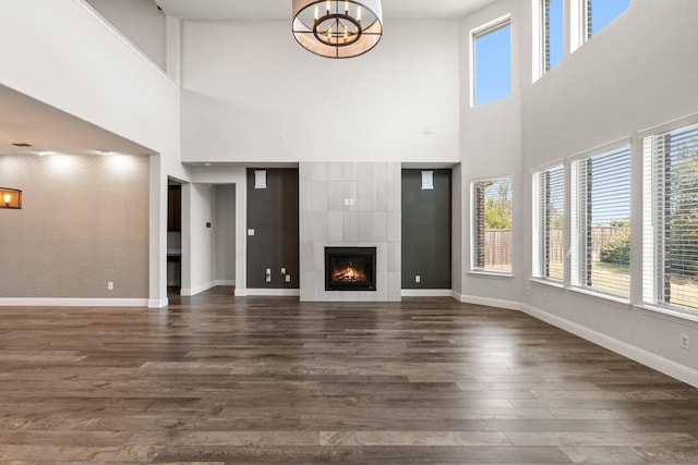 unfurnished living room with a tile fireplace, dark wood finished floors, and baseboards