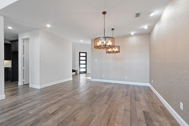 unfurnished room with a chandelier, recessed lighting, wood finished floors, visible vents, and baseboards