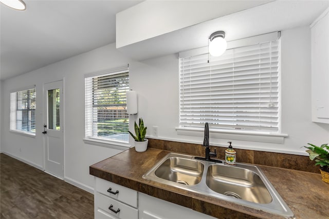 kitchen featuring dark countertops, a sink, dark wood finished floors, and white cabinets