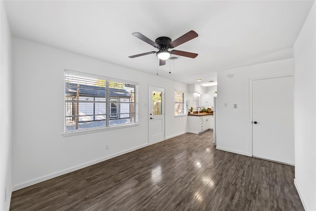 unfurnished living room featuring a ceiling fan, dark wood-style flooring, and baseboards