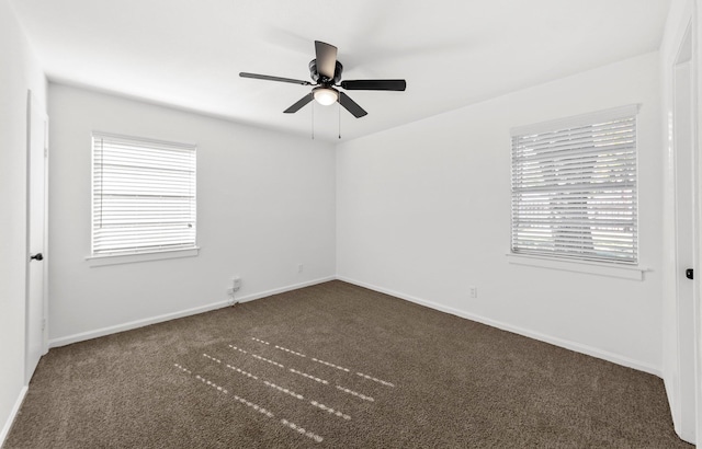 spare room featuring dark colored carpet, ceiling fan, and baseboards