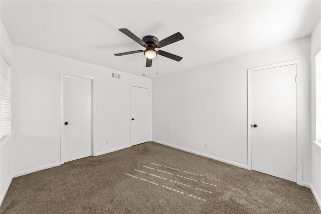 unfurnished bedroom featuring ceiling fan, visible vents, dark colored carpet, and baseboards