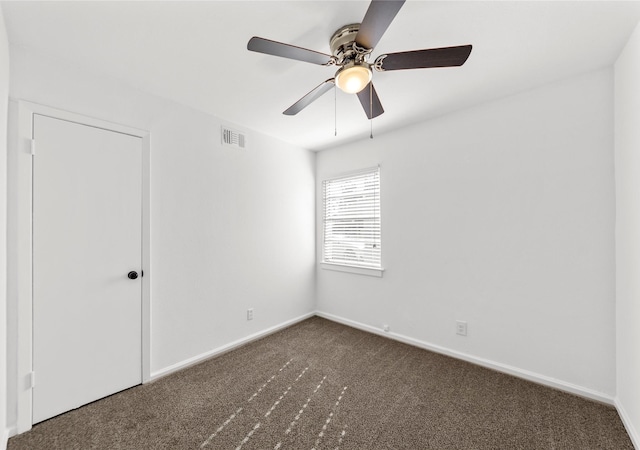 empty room featuring a ceiling fan, visible vents, dark carpet, and baseboards