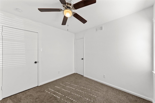 unfurnished bedroom with a ceiling fan, dark colored carpet, visible vents, and baseboards