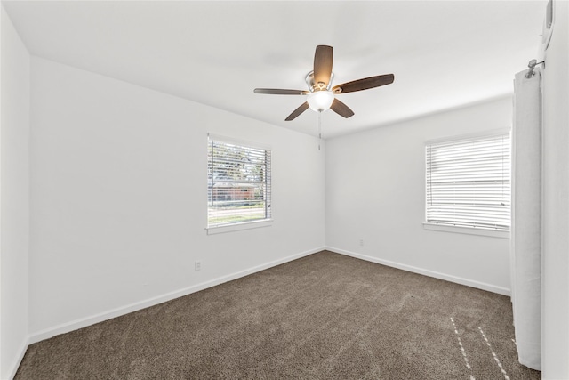 empty room featuring ceiling fan, baseboards, and dark colored carpet