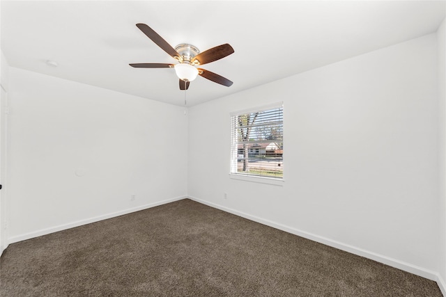 empty room featuring baseboards, dark carpet, and ceiling fan