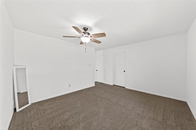 interior space with a ceiling fan, dark colored carpet, and baseboards