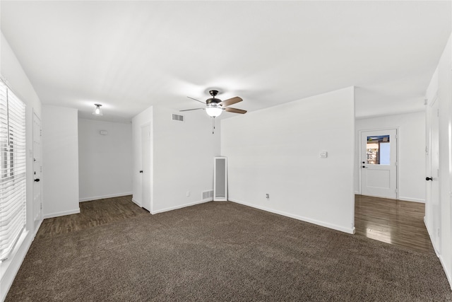 spare room featuring baseboards, visible vents, and dark carpet