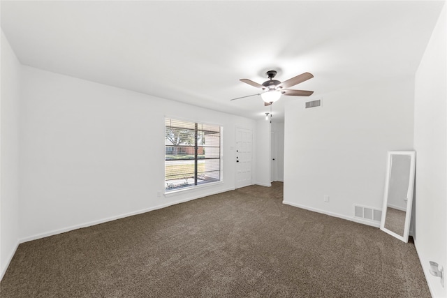 empty room with a ceiling fan, visible vents, dark carpet, and baseboards