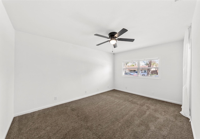 empty room with baseboards, dark colored carpet, and a ceiling fan