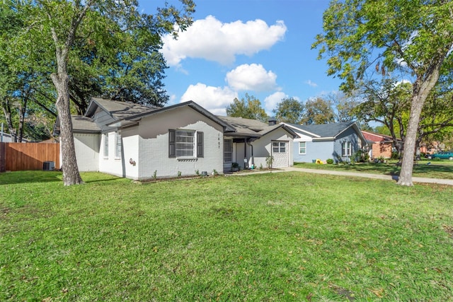 ranch-style house with a front yard, brick siding, fence, and central AC unit