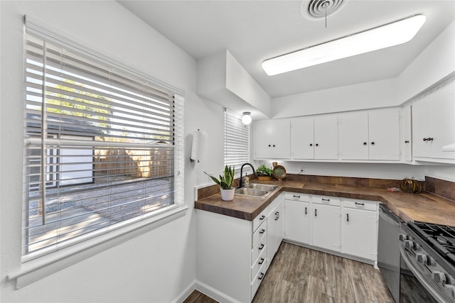 kitchen with dark countertops, stainless steel appliances, white cabinets, and a sink