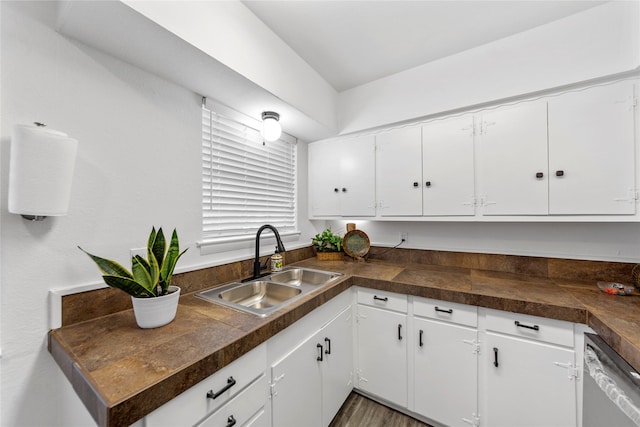 kitchen with tile countertops, stainless steel dishwasher, a sink, and white cabinets