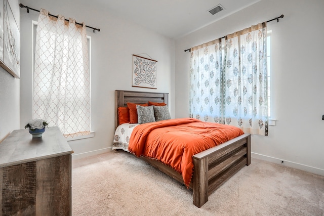 bedroom featuring baseboards, visible vents, and light colored carpet
