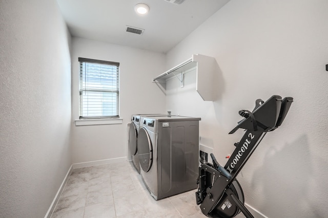 clothes washing area with light tile patterned floors, laundry area, visible vents, baseboards, and washer and dryer