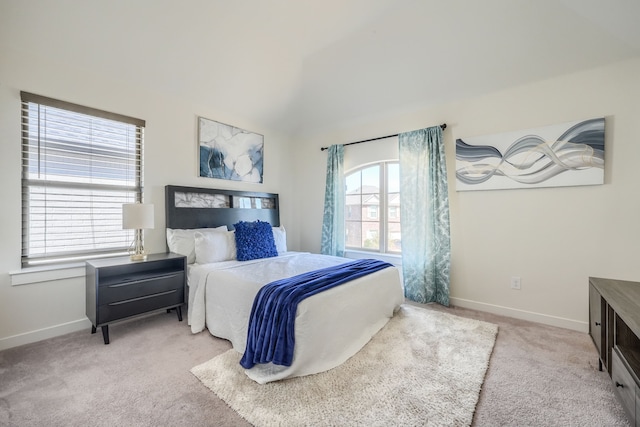 bedroom featuring light colored carpet, vaulted ceiling, and baseboards