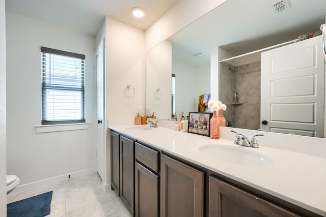 bathroom featuring double vanity, visible vents, toilet, and a sink