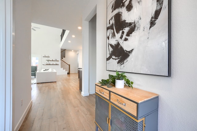 hall featuring wood-type flooring, stairs, baseboards, and recessed lighting