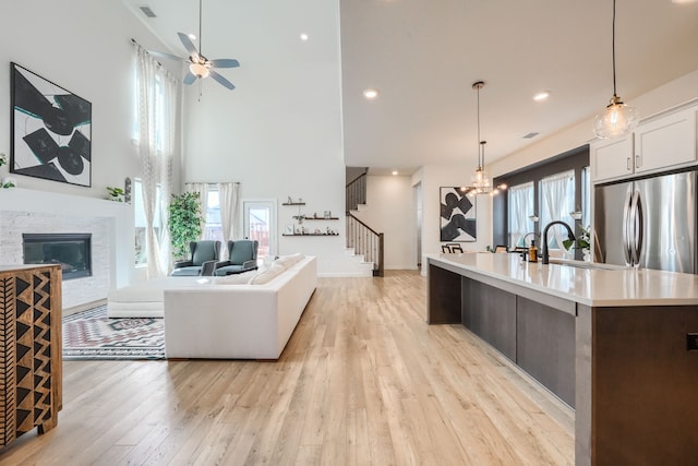 kitchen featuring a fireplace, white cabinets, open floor plan, light countertops, and stainless steel fridge