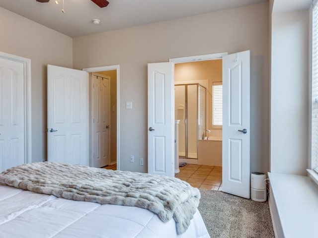 bedroom featuring ensuite bathroom, light tile patterned floors, and a ceiling fan