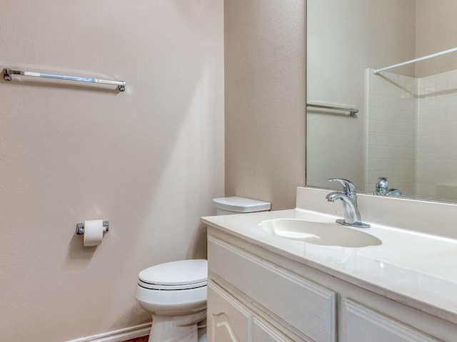 bathroom with a shower, vanity, toilet, and baseboards