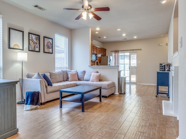 living room featuring baseboards, visible vents, a ceiling fan, light wood-style floors, and recessed lighting