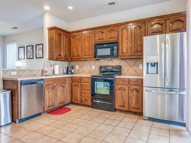 kitchen with visible vents, light countertops, brown cabinets, decorative backsplash, and black appliances