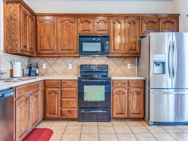 kitchen with a sink, black appliances, light tile patterned floors, and light countertops