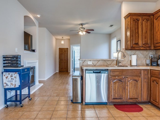 kitchen with visible vents, brown cabinets, light countertops, stainless steel dishwasher, and a sink