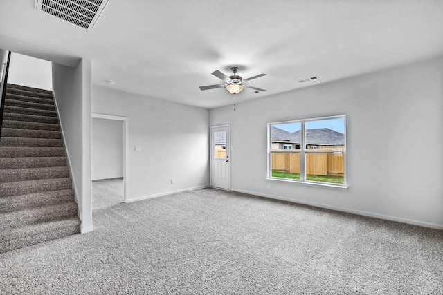 empty room featuring carpet floors, stairs, and visible vents