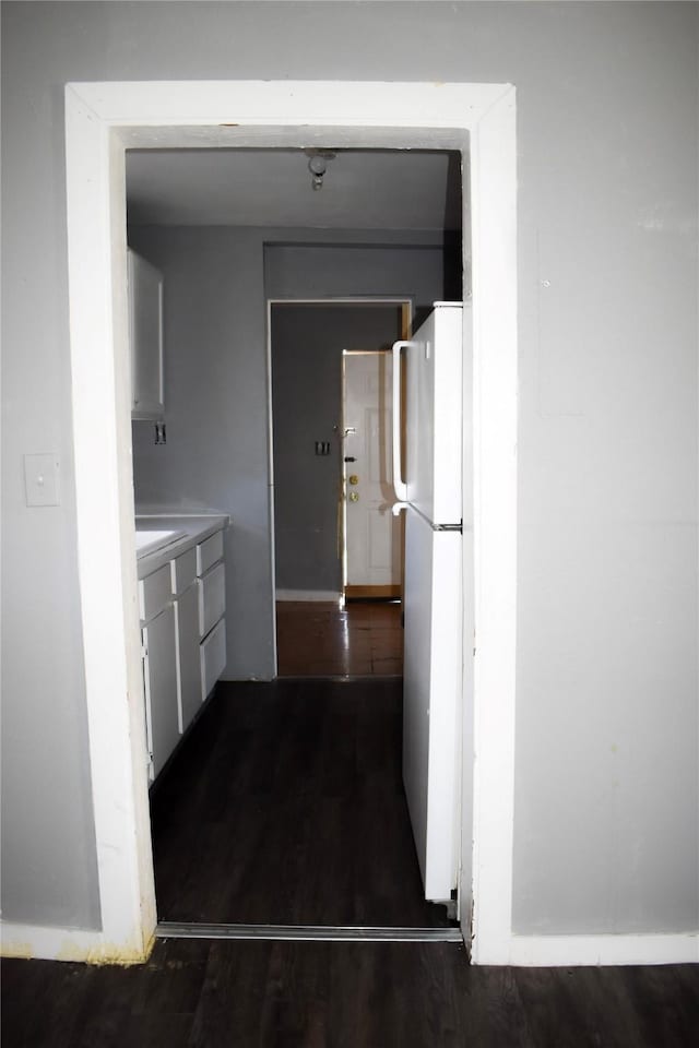 kitchen featuring dark wood-style floors, freestanding refrigerator, and light countertops