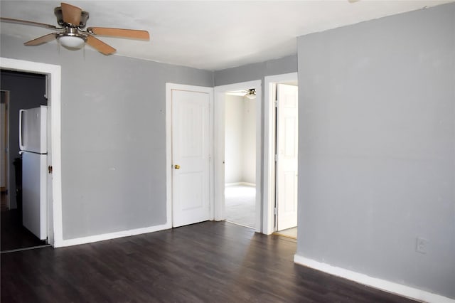 unfurnished room with dark wood-style floors, ceiling fan, and baseboards