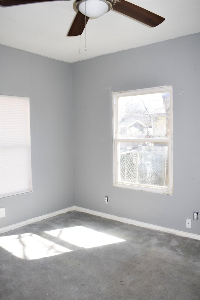 carpeted spare room featuring baseboards and a ceiling fan