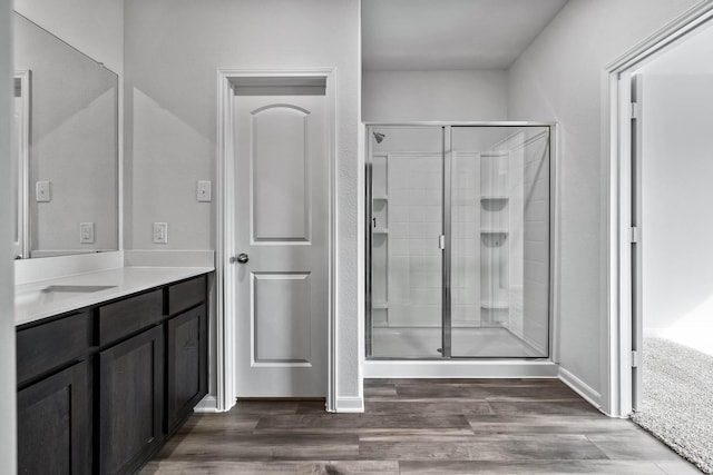 bathroom with a shower stall, baseboards, wood finished floors, and vanity