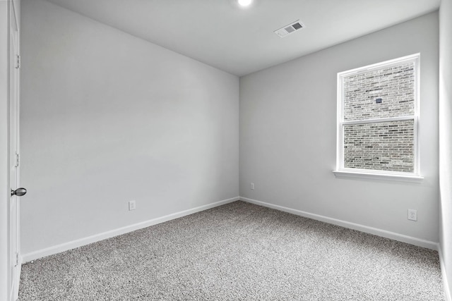 spare room featuring carpet, visible vents, and baseboards