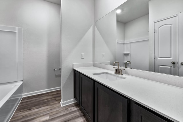 full bath featuring wood finished floors, vanity, and baseboards