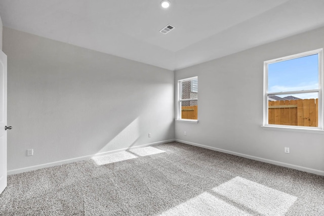 spare room with carpet floors, visible vents, and baseboards