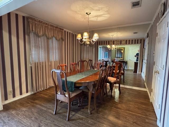 dining room with a chandelier, dark wood-style flooring, visible vents, and wallpapered walls