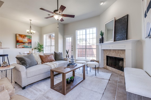 living area featuring tile patterned floors, ceiling fan with notable chandelier, and a tile fireplace