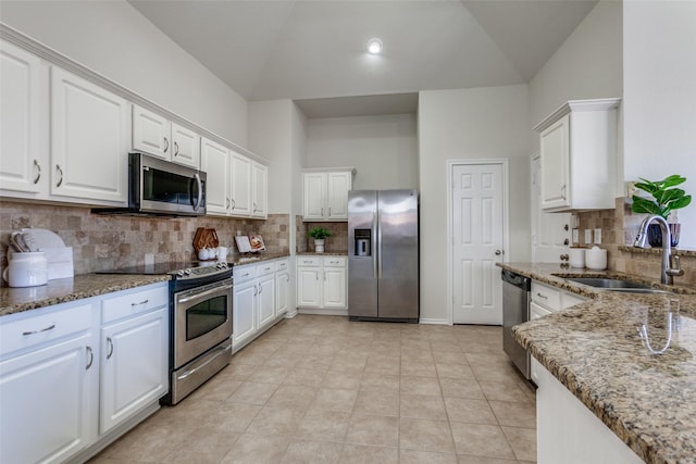 kitchen featuring appliances with stainless steel finishes, white cabinetry, a sink, and dark stone countertops