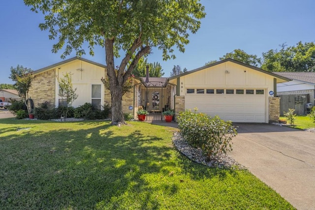 ranch-style home with driveway, brick siding, a front lawn, and an attached garage