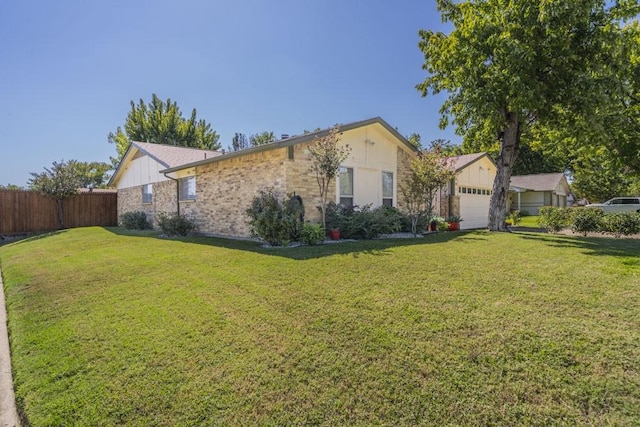 view of front of house with brick siding, an attached garage, a front yard, and fence