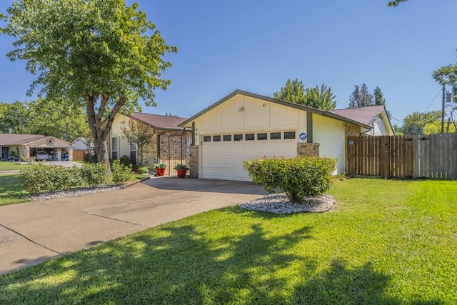 view of front of house featuring concrete driveway, a front lawn, an attached garage, and fence